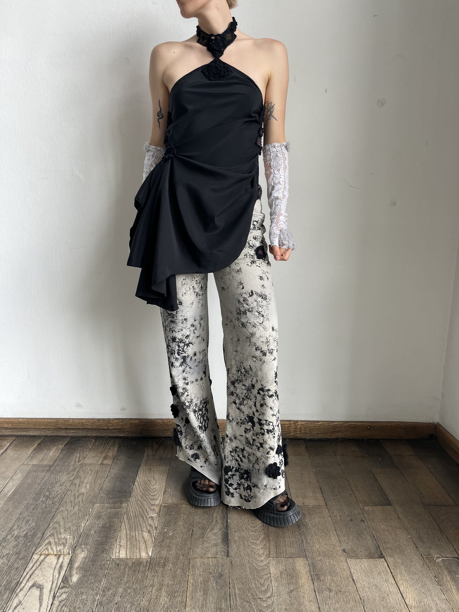Model in bedruckter Jeanshose und schwarzem Neckholder-Häkeltop