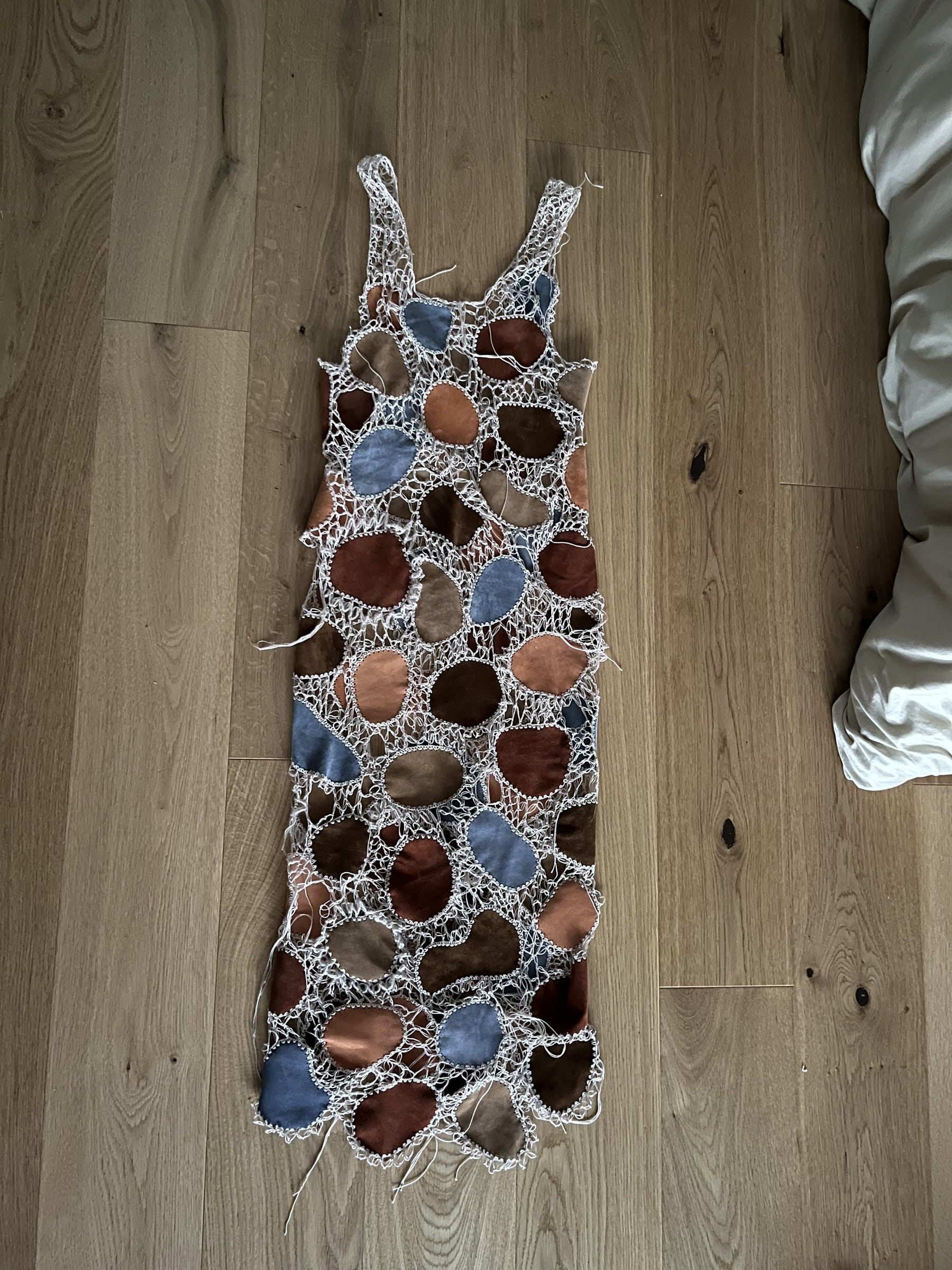 Das fertige bodenlange Häkel-Lederkleid auf Holzboden liegend